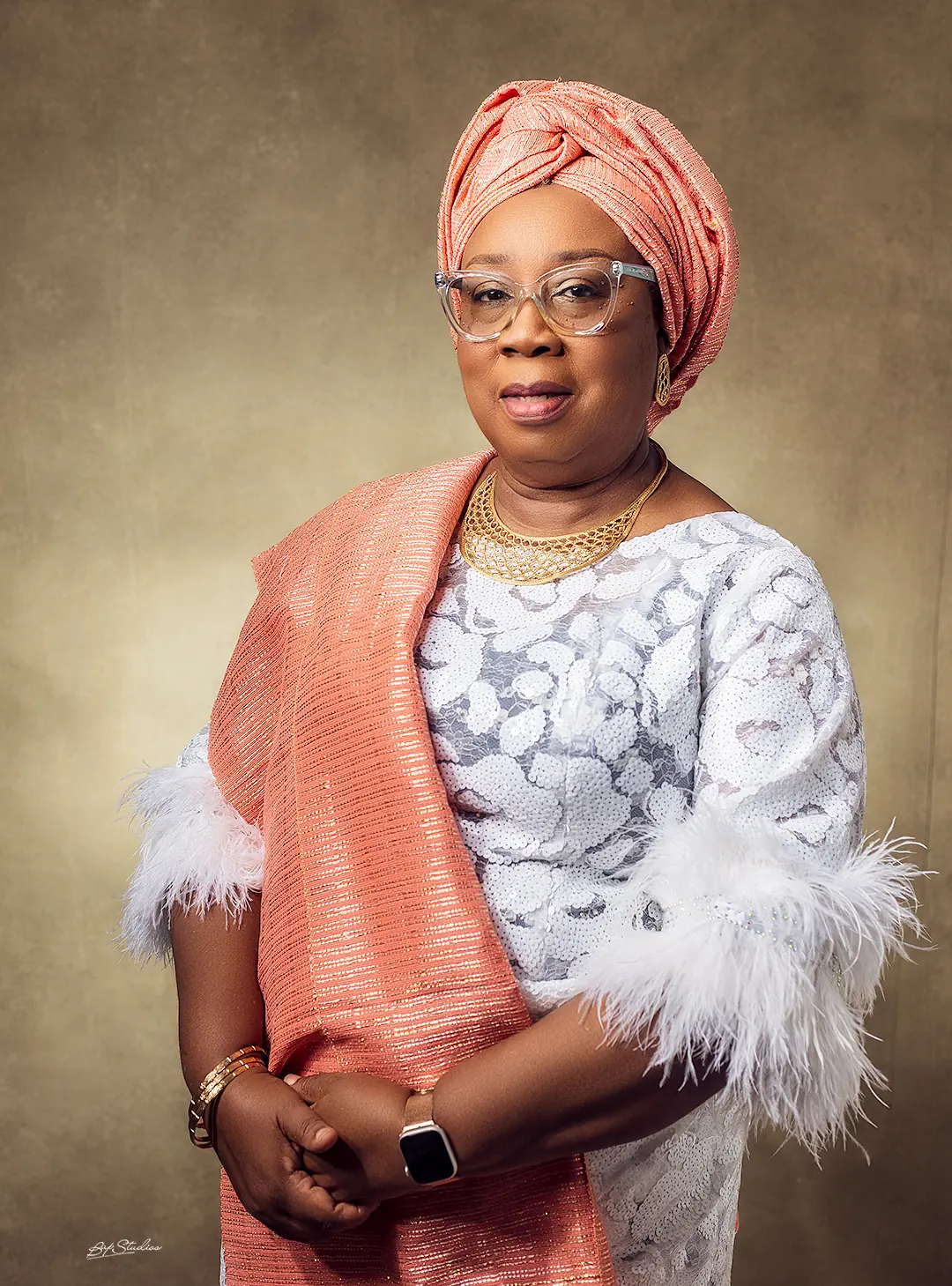 Folasade Adefisayo in a silver-grey lace gown with a coral head-tie and shawl.
